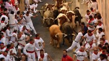 Revellers run in front of Cebada Gago fighting bulls during the first running of the bulls at the San Fermin Festival, in Pamplona, northern Spain, Friday, July 7, 2017.